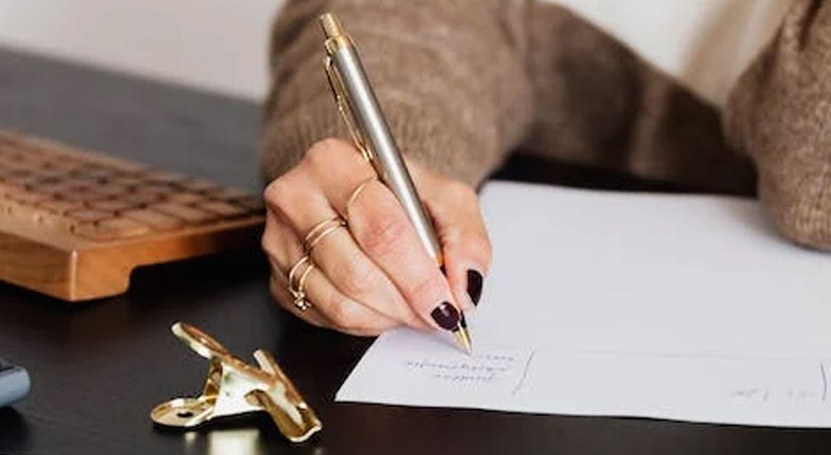 Picture of a person writing on a sheet of paper